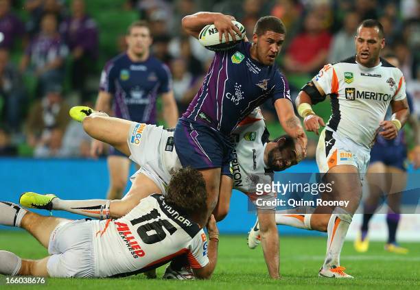 Kenny Bromwich of the Storm is tackled by Matt Bell and Aaron Woods of the Tigers during the round 5 NRL match between the Melbourne Storm and the...