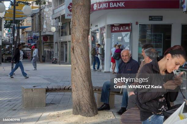 People sit on benches in the street outside Laki Bank on March 30, 2013 in Nicosie,Cyprus.