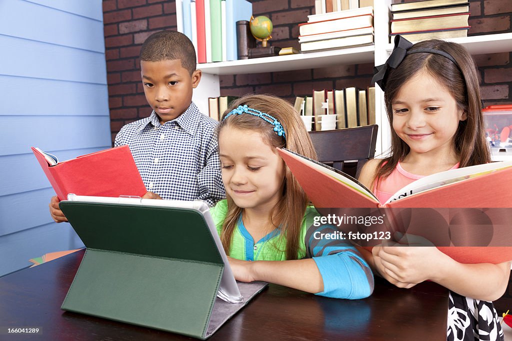 Multi-ethnischen elementaren Schülern. Schule Klassenzimmer. Digitale tablet und Bücher.