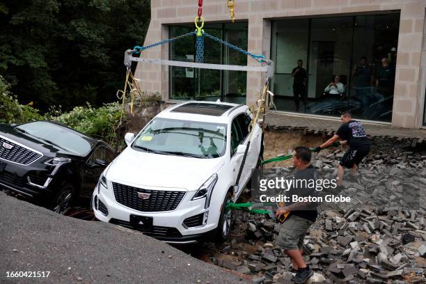Leominster, MA Workers use a crane to remove cars from a sinkhole that opened up at a Cadillac dealership.