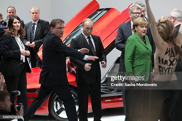 Russian President Vladimir Putin is attacked by an activist of the Ukrainian women rights group 'Femen' as German Chancellor Angela Merkel looks on...