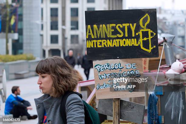 Woman walks past a sign of Amnesty Internationalduring a protest against discrimination of Roma people in Europe, on April 8, 2013 in Brussels. AFP...