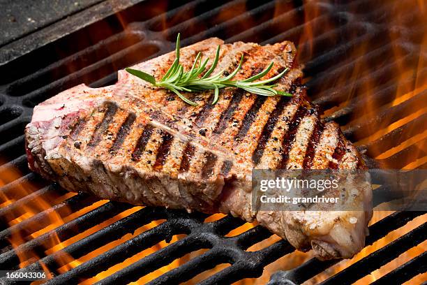 t-bone steak auf dem grill mit flammen - t bone steak stock-fotos und bilder