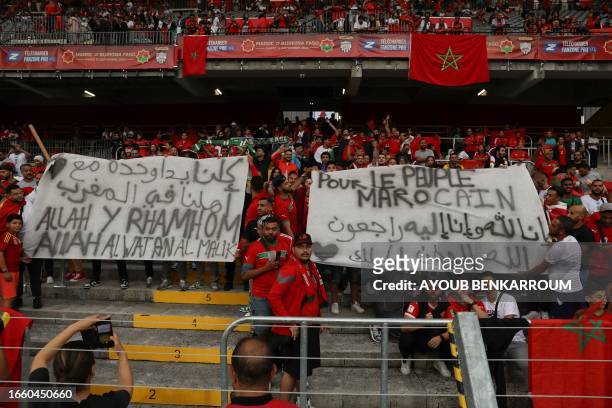 Supporters of Morocco hold banners reading "For the people of Morocco" ahead of the international friendly football match between Morocco and Burkina...