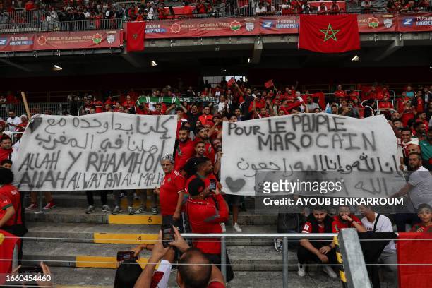 Supporters of Morocco hold banners reading "For the people of Morocco" ahead of the international friendly football match between Morocco and Burkina...