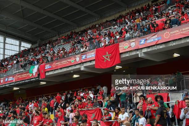 Supporters of Morocco hold Moroccan flags ahead of the international friendly football match between Morocco and Burkina Faso at the Stade...