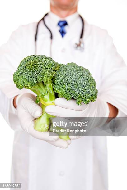doctor holding raw broccoli - se stockfoto's en -beelden