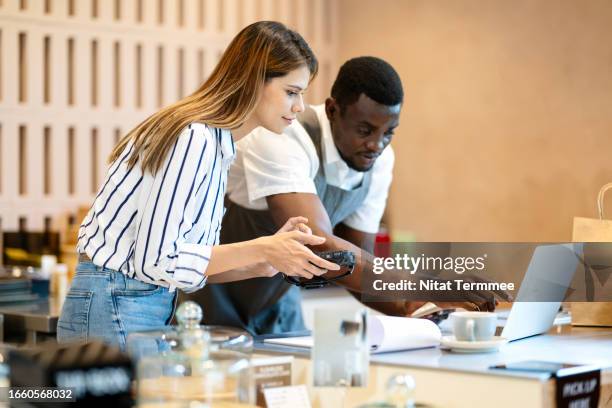 start and grow a successful restaurant business with financial planning. coffee shop partners are discussing a cash flow plan and expenses of operations via a laptop computer at a cashier counter. - franchising stock pictures, royalty-free photos & images
