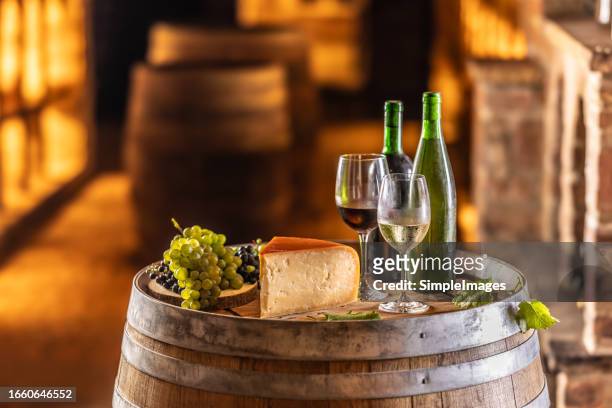 white and red wine with grapes and cheese on a wooden barrel in a wine archive cellar. concept of winery and grape products. concept of wine production. - czech republic wine stock pictures, royalty-free photos & images