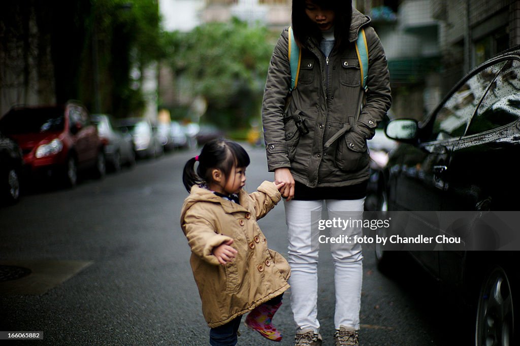 Girl walking with mom in a raining day