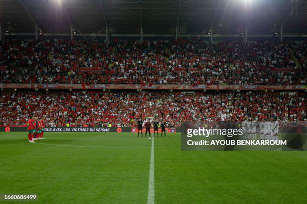 Morocco players , Burkina Faso players and the officiating team stand in the centre circle as they hold a moment of silence for the victims of the...
