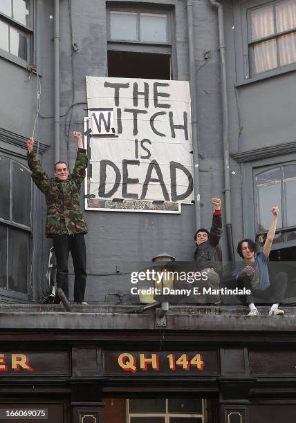 People cheer in front of a banner displaying the message 'The Witch is Dead' as they celebrate the death of former British Prime Minister Margaret...