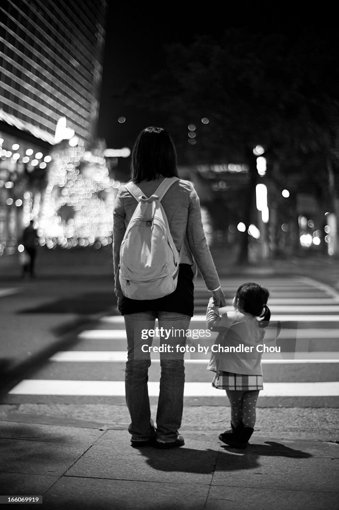 Girl holding her mom's hand cross road