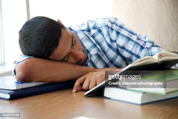 a tired hispanic student sleeping with his book open - tire stack stock pictures, royalty-free photos & images