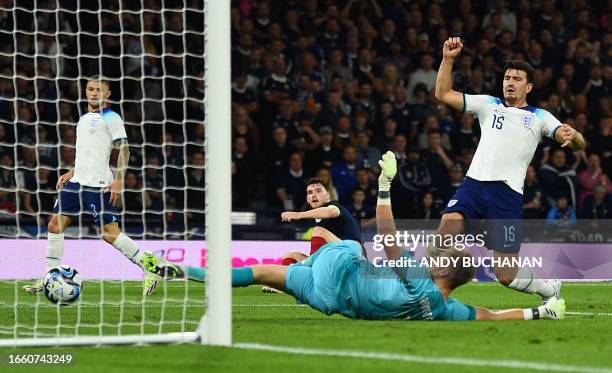 Scotland's defender Andrew Robertson celebrates as England's defender Harry Maguire reacts after scoring an own goal during the international...