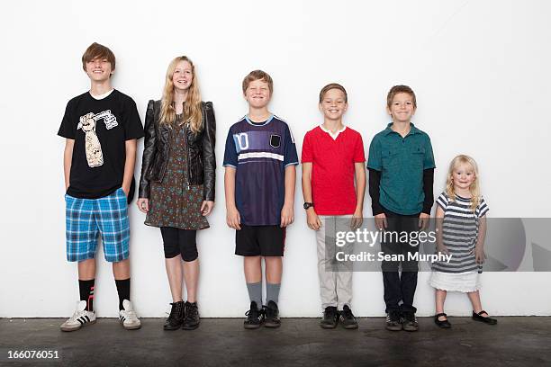 group of sibling in line against white wall - brother toddler sister stockfoto's en -beelden