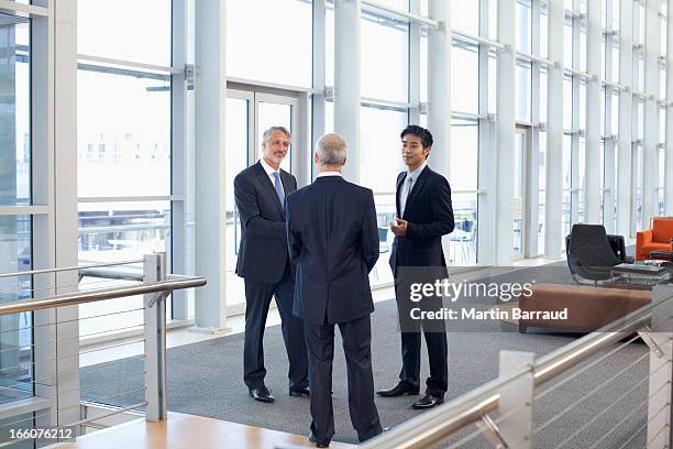 business people meeting at window in office lobby - three people standing stock pictures, royalty-free photos & images