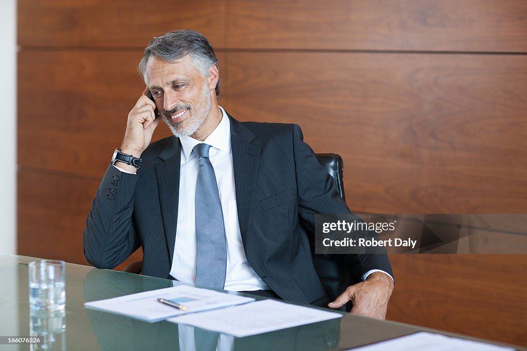 Smiling businessman talking on cell phone in conference room