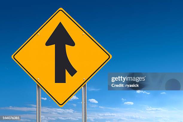 merge converge ahead road sign post over blue sky background - merging sign stockfoto's en -beelden