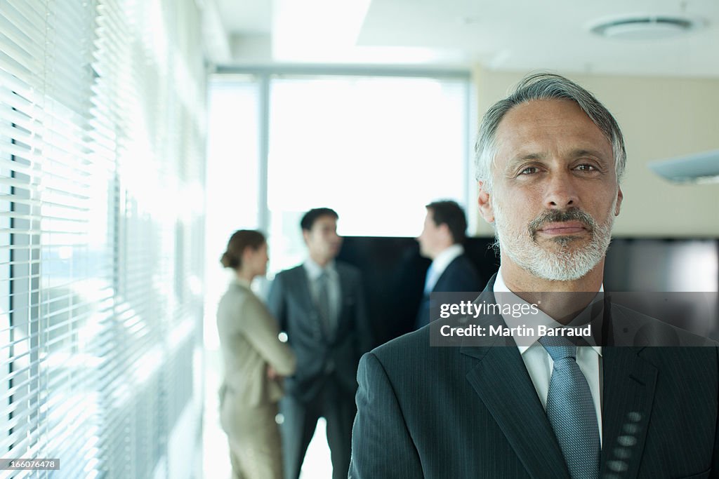 Portrait of smiling businessman with co-workers in background