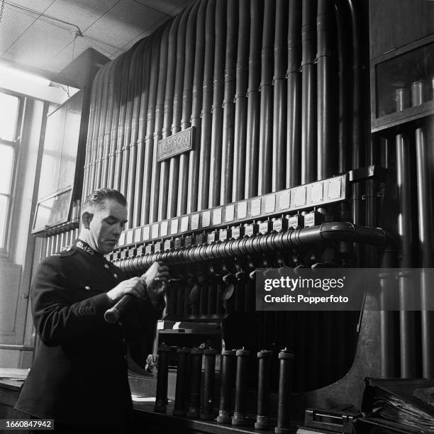 Metropolitan Police officer sends a message via a pneumatic tube system linking all departments at the New Scotland Yard building on Victoria...