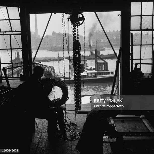 Civilian boatbuilding experts from the Metropolitan Police Thames Division at work in a repair workshop overlooking River Police motor launches...