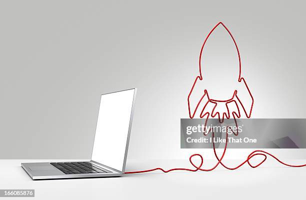 laptop computer with cable forming a rocket - rocket internet stockfoto's en -beelden