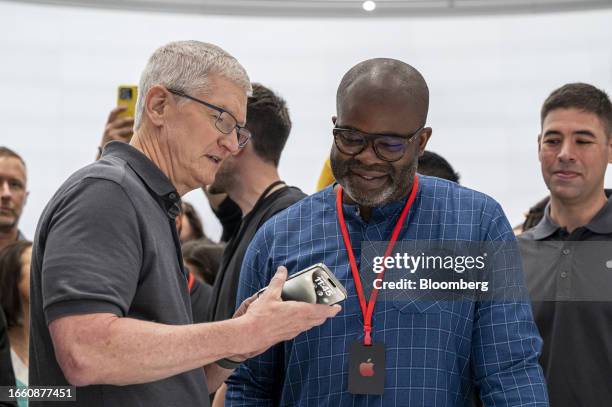 Tim Cook, chief executive officer of Apple Inc., left, holds an iPhone 15 Pro Max during an event at Apple Park campus in Cupertino, California, US,...