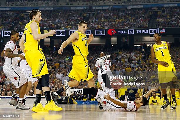 Peyton Siva of the Louisville Cardinals falls to the court as he loses the ball against Nik Stauskas, Mitch McGary and Glenn Robinson III of the...