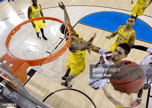 Peyton Siva of the Louisville Cardinals drives for a shot attempt in the first half against Glenn Robinson III of the Michigan Wolverines during the...