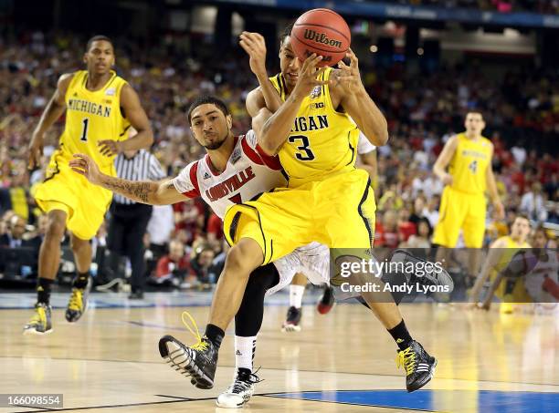 Trey Burke of the Michigan Wolverines attempts to control the ball in the second half against Peyton Siva of the Louisville Cardinals during the 2013...