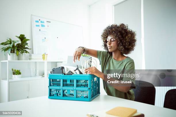 woman collecting electronic waste in the office - elektronisch afval stockfoto's en -beelden