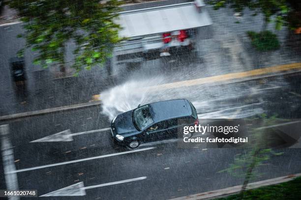 car driving fast through flooded roadway and spraying people standing in a bus stop - car splashing water on people stock pictures, royalty-free photos & images