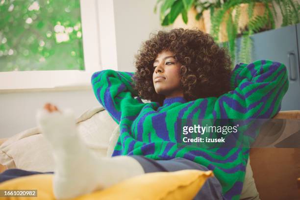 sad young woman with broken leg resting at home - jade stock pictures, royalty-free photos & images