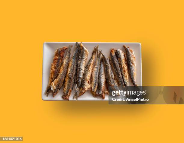 still life with a tray of fried anchovies on a y ellos background - anchovy fotografías e imágenes de stock