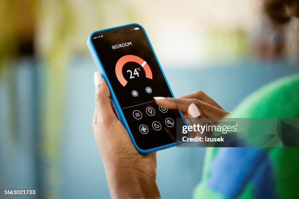 woman using mobile phone to control termostat at home - gesture control screen imagens e fotografias de stock