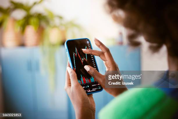 femme regardant les graphiques boursiers - femme de dos smartphone photos et images de collection