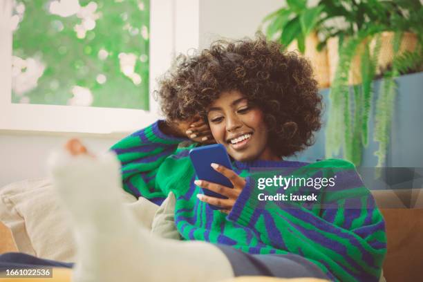 young woman with broken leg using mobile phone - women injury stock pictures, royalty-free photos & images