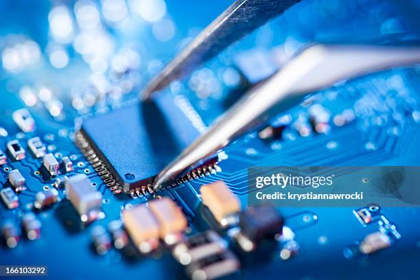 electronic technician holding tweezers and assemblin a circuit board. - elektronica stockfoto's en -beelden