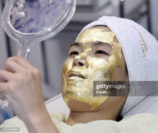 Female guest is covered with pure gold foil as she receives gold facial treatment by Japan's beauty company Umo for anti aging treatment at the...