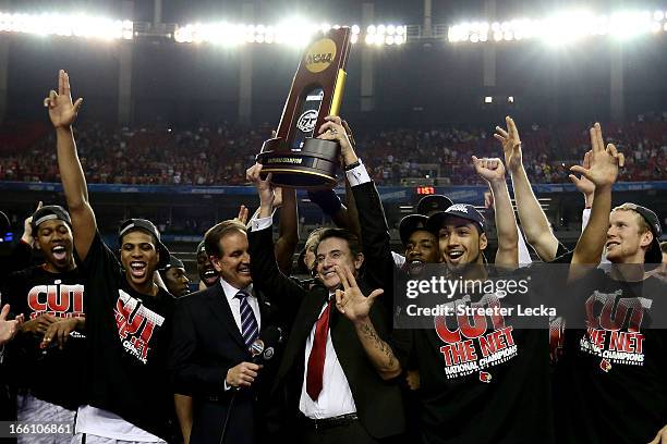 Head coach Rick Pitino of the Louisville Cardinals holds up the National Championship trophy as he celebrates with his players including Peyton Siva...