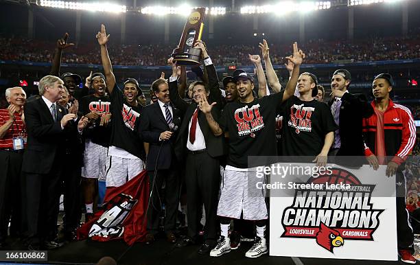 Head coach Rick Pitino of the Louisville Cardinals holds up the National Championship trophy as he celebrates with his players including Peyton Siva