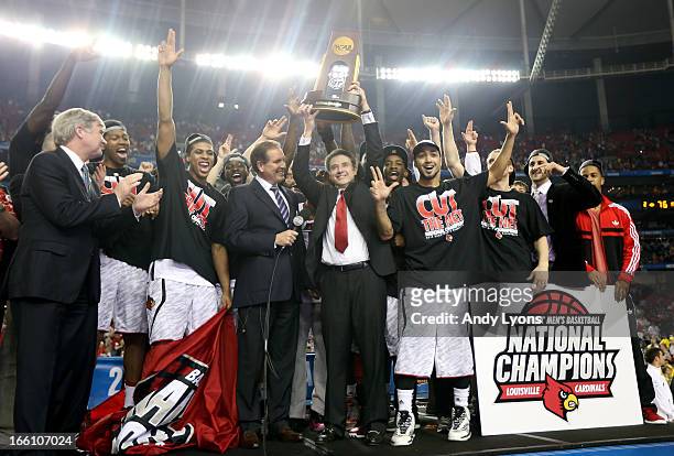 Head coach Rick Pitino of the Louisville Cardinals holds up the National Championship trophy as he celebrates with his players including Peyton Siva
