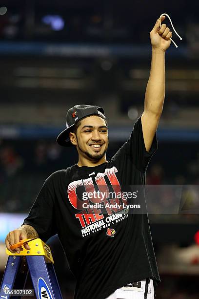 Peyton Siva of the Louisville Cardinals celebrates after he cut down a piece of the net after they won 82-76 against the Michigan Wolverines during...