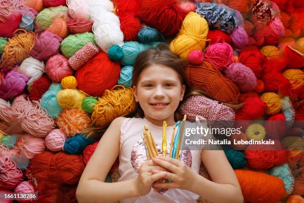 creativity and needlework: happy baby girl with bunch of crochet hooks lies on colorful balls of yarn. creative abundance - baby cotton wool stock pictures, royalty-free photos & images