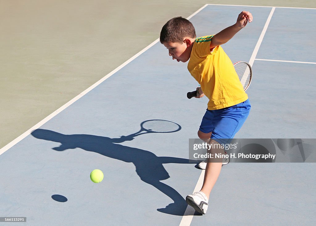 Boy playing tennis in sunny day