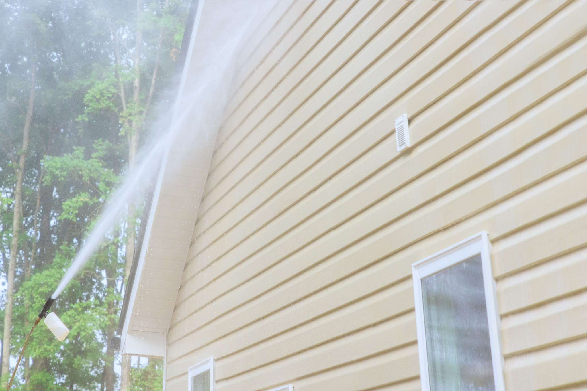 Using high pressure nozzles, service man efficiently washes siding houses with water and soap cleaner Using high pressure nozzles, service man efficiently washes siding houses with water and soap cleaner