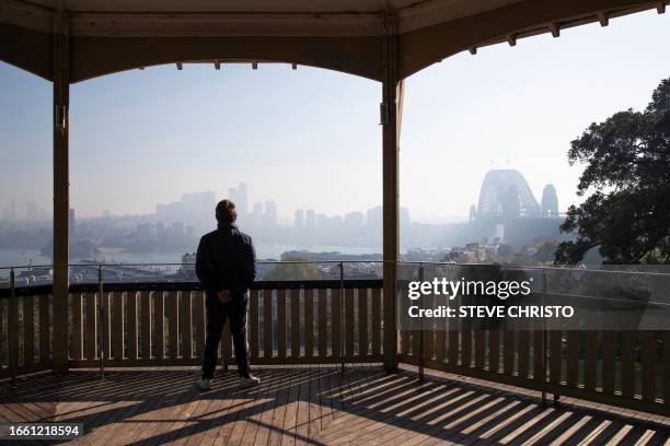 Man looks out from his balcony at the Sydney skyline on September 13 as a smoky haze blankets Australia's scenic Sydney Harbour, after a ring of...