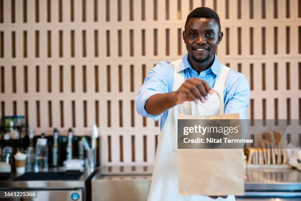 build customer experience in your restaurants must serve now to increase revenues. a male african-american barista gives a take-out coffee to his customer at a counter. - carry on bag bildbanksfoton och bilder