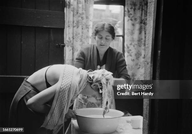 Woman shampooing another's hair at home over a large bowl, 1954. Original Publication: Picture Post - 7045 - Usherette - unpub. 1954.